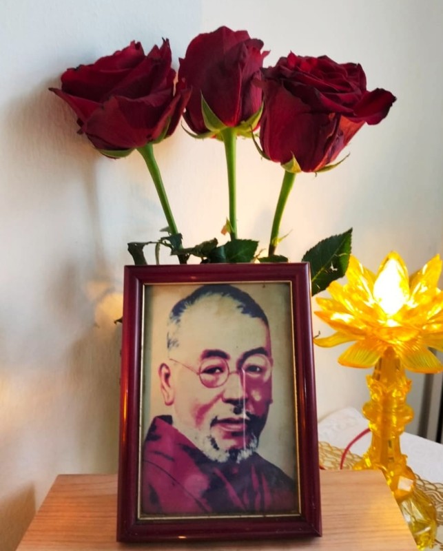 Tribute to Dr. Mikao Usui, Founder of Reiki Framed portrait of Dr. Mikao Usui, founder of Reiki, placed on a wooden altar with three red roses and a glowing lotus lamp as a tribute display.
